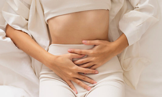 Frau mit Endometriose hält sich den Bauch – Darstellung der Verbindung zwischen Darm, Mikrobiom, Entzündungen und hormonellem Ungleichgewicht